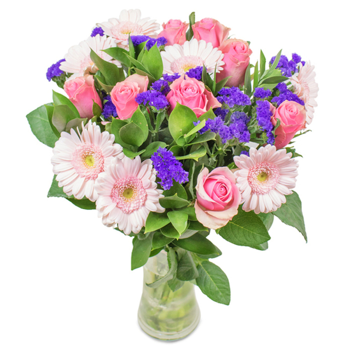 An elegantly constructed bouquet showcased in a slender, clear glass vase on a bright backdrop, this arrangement epitomizes the refined energy of Southfields. Around seven to nine classic pink roses, their petals in stages from tight bud to graceful bloom, form the heart of the display-each rose carefully placed to maximize its unique beauty. Surrounding these are five to seven pale pink gerbera daisies, large and open-faced, their delicately edged petals softening the entire composition. Accents of vivid violet or purple statice provide vibrant contrast throughout, their springy clusters mirroring the colourful borders seen along Wimbledon Park Road. The dark, lush greenery frames the flowers and adds a finishing touch of natural fullness, while visible stems in clear water infuse a sense of just-picked freshness-that feeling you might get after a stroll through Coronation Gardens. This bouquet is a perfect gift for special days such as birthdays, anniversaries, or to say thank you to someone in Southfields, and is prepared by skilled hands familiar with the neighbourhood's unique tastes and occasions.
